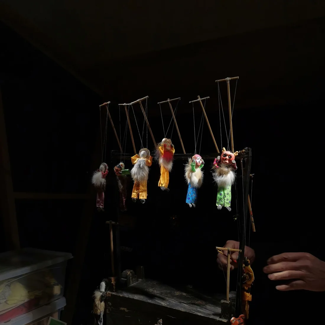 Marionetas de hilos colgadas de sus crucetas en la penumbra de un taller